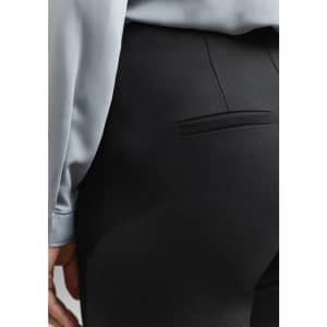 A close-up of black women's leggings, featuring a back pocket and part of a light blue top.