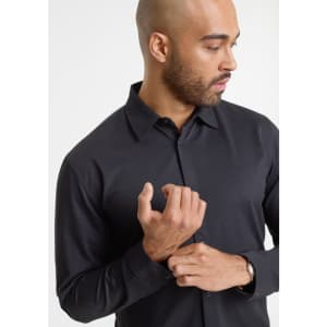 A black long sleeve shirt on a model, featuring a collar and button-up design. The model is adjusting his shirt.