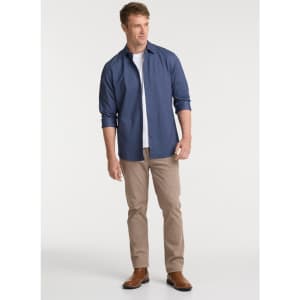 A man wears a navy long sleeve shirt with rolled sleeves, paired with light tan pants and brown boots.