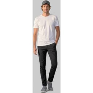 A man wearing black Venture Pants and a white t-shirt, with a grey cap and shoes, standing against a plain background.
