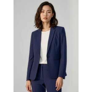 A woman wearing a navy blue blazer, styled with a white top, featuring a logo on the garment.