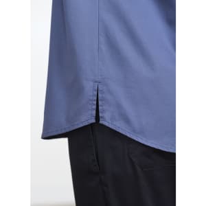 A blue short sleeve chef shirt with a split hem, paired with dark trousers, featuring a logo.