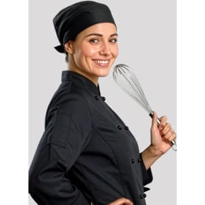 A chef in a black uniform and black bandana holds a whisk, smiling against a grey background.