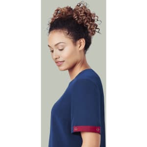 A navy blue unisex scrub top with a burgundy accent on the sleeves, featuring a logo.