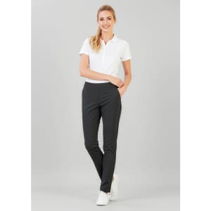 A woman stands in fitted black stretch pants paired with a white polo shirt and white sneakers.