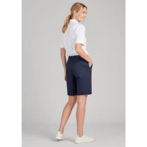 A woman stands wearing navy cargo shorts with a fitted white shirt, showcasing the back view and side pockets.