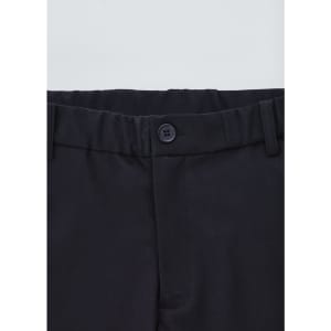 A close-up of black cargo pants featuring a button closure and elastic waistband. Logo present.