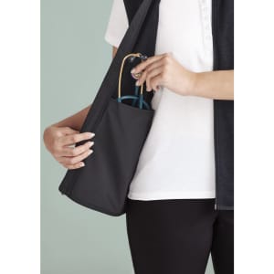 A person holds a black vest with a side pocket, featuring blue sunglasses. The vest has a zip front and a sleek design.