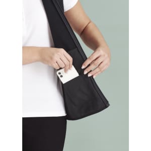 A black women's zip front vest with a hand inserting a phone into a side pocket. The fabric appears smooth and stretchy.