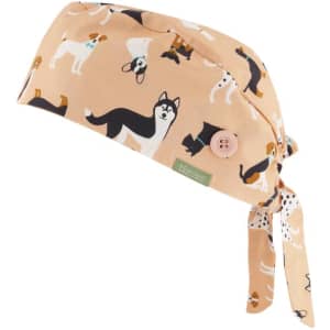 A unisex scrub cap in a light peach colour, featuring a pattern of various dogs and a button detail.