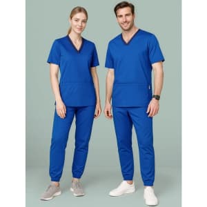 A man and woman wearing blue scrub tops and slim leg jogger scrub pants, with a logo present on the apparel.