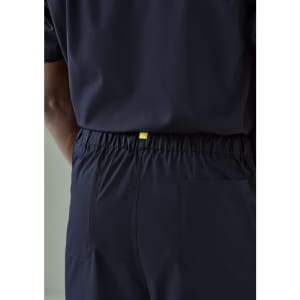 Navy unisex scrub pants with an elastic waistband and a back pocket, featuring a branding tag.
