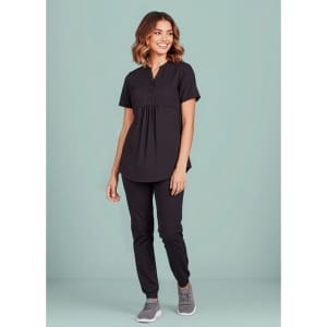 A black women's tunic scrub top is worn with matching pants, featuring a relaxed fit and button detail.