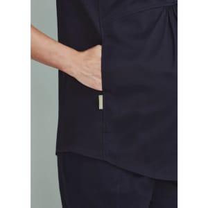 A navy women's scrub tunic top featuring a side pocket and a simple design. It includes a branding logo.