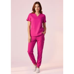 A women's pink v-neck scrub top paired with matching pink scrub pants, featuring pockets and a logo.