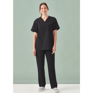 A woman wearing a black unisex pulse V-neck scrub top paired with matching black scrub pants, standing against a light background.