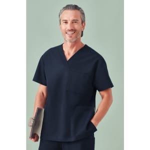 A unisex navy pulse V-neck scrub top with a pocket, modelled by a smiling man holding a clipboard.