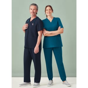 A unisex scrub top in navy and teal, worn by a male and female model, with a stethoscope and casual grey shoes.
