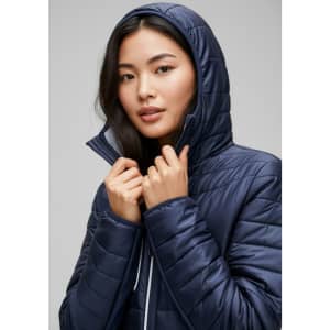 A woman in a navy unisex patrol jacket with a hood, adjusting the collar, featuring a sleek design.