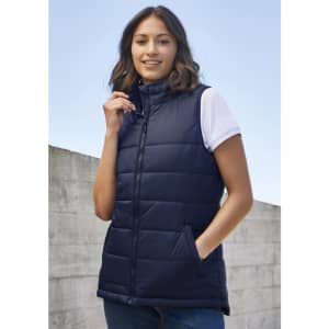 A women's navy Alpine vest with a zip front and side pockets, styled over a white top. It features a logo.