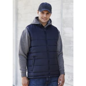 A navy men's alpine vest, featuring a zip front and side pockets, worn over a grey hoodie. The model is smiling and wearing a cap.