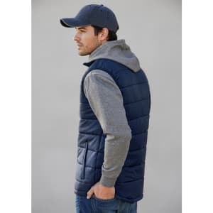 A navy men's alpine vest with grey hooded sleeves, featured on a model facing sideways. The vest has a logo.