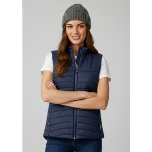 A navy women's expedition vest featuring a zip front and a grey knitted beanie. The model is smiling with arms crossed.