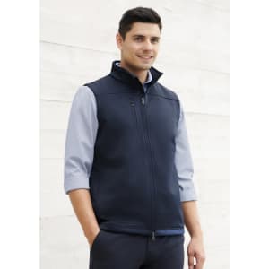 A navy blue men's softshell vest with a zip front and a logo, worn over a light blue shirt.