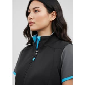 A woman models a black vest with blue accents, featuring a stand-up collar and a zipper. The vest has a logo.