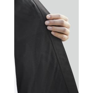 A hand holds the edge of a Women's Tempest Jacket, showcasing its black fabric texture and design.