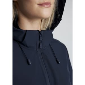 A close-up of a woman wearing a navy blue jacket with a hood, featuring a zip and adjustable drawstrings.