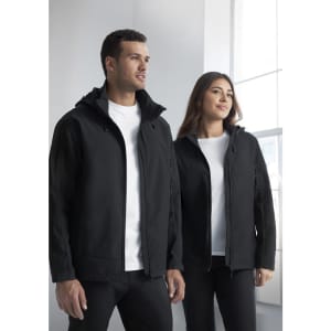 A black rain jacket is worn by a man and a woman, both posing indoors near a window. The jacket features a hood and has a logo.