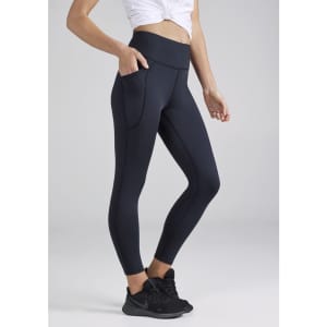 A pair of navy women's 7/8 length leggings with pockets, complete with a logo, worn with a white top and black shoes.