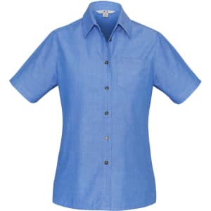 A women's short sleeve button-up shirt in light blue chambray fabric, featuring a single chest pocket and a branded logo.