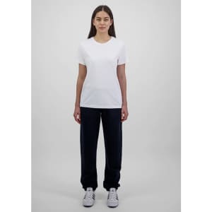 A woman stands wearing a white t-shirt and navy blue track pants, showcasing a simple, casual outfit.