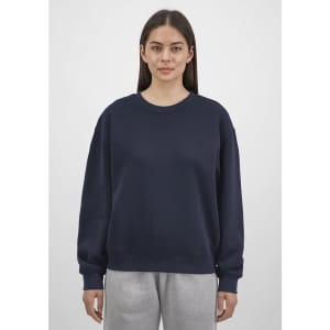 A navy crew sweatshirt for women featuring a relaxed fit, paired with grey sweatpants. It has a logo on the front.