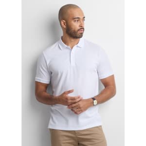 A white short sleeve polo shirt is worn by a man standing against a neutral background, featuring a subtle logo.
