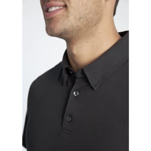 A close-up of a black men's polo shirt featuring a collar and buttons, with a branding logo present.