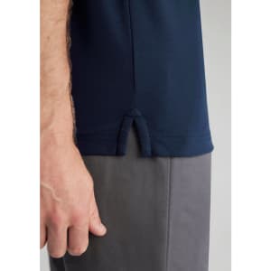 A dark navy blue men's polo shirt featuring a vented hem, with a model's hand visible holding the shirt.