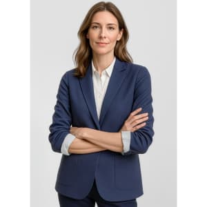A navy blue women's blazer with a tailored fit and a branding logo. The model has arms crossed, displaying the jacket.