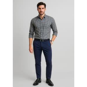 A man stands wearing a checkered grey shirt and navy tapered stretch chino pants, finished with black shoes and a belt.