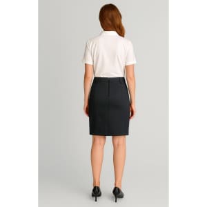 A woman in a white polo shirt and dark mid waist stretch chino skirt, facing away from the camera.