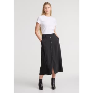 A woman wears a black midi skirt with a front slit and buttons, paired with a simple white T-shirt.