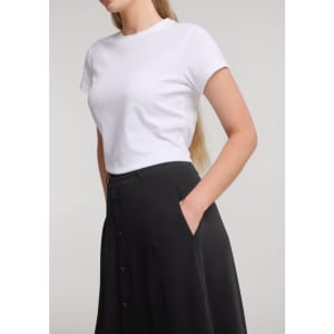 A women's black skirt with buttons, paired with a plain white t-shirt, featuring pockets on the side.