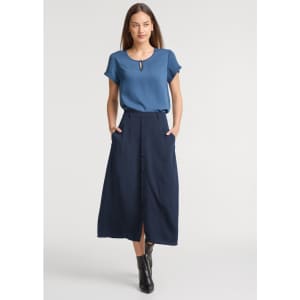A women's short sleeve blouse in blue, paired with a long navy skirt. The model has a logo on the blouse.