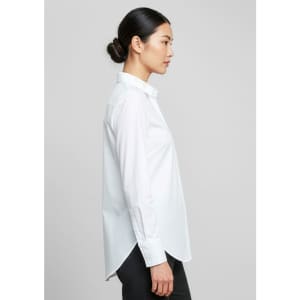 A long-sleeve white button-up shirt with a straight cut and side splits, featuring a logo on the label.