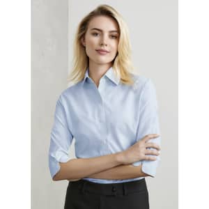 A light blue women's button-up shirt with 3/4 sleeves, featuring a collar and a logo.