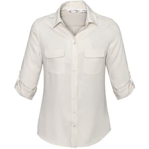 A women's long sleeve button-up shirt in cream, featuring two front pockets and rolled-up sleeves. It has a logo.