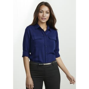 A navy blue long sleeve button-up shirt featuring two front pockets and rolled sleeves. It has a logo.