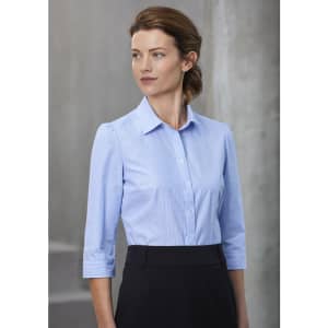 A women's button-up shirt in light blue, featuring 3/4 sleeves, with a collar and a fitted design. It has a logo.